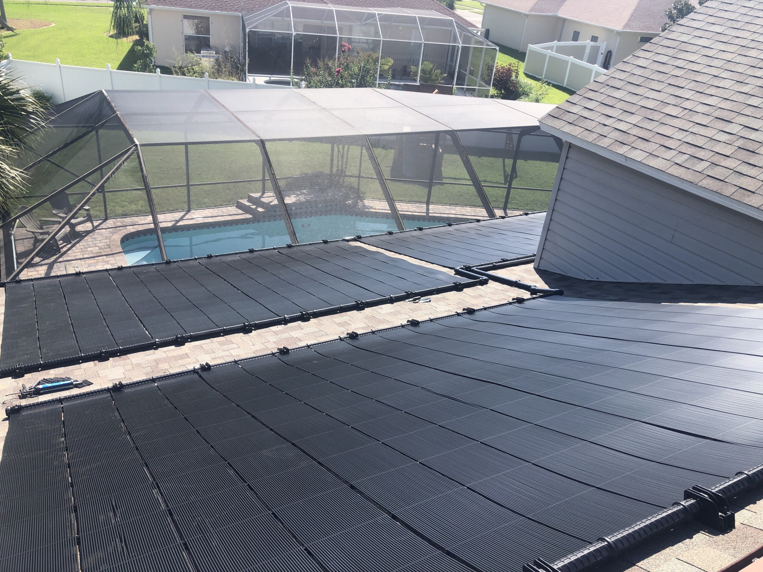 Rooftop solar pool heating collectors overlooking a screened swimming pool