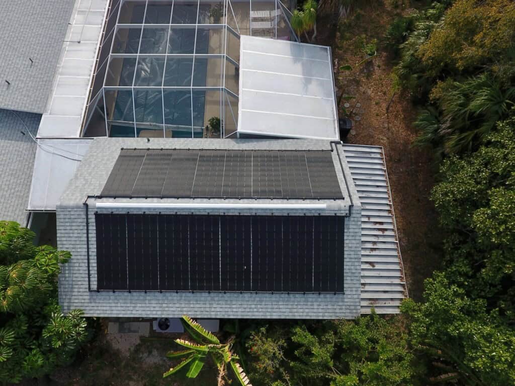 Aerial view of rooftop solar pool heating collectors above a screened swimming pool