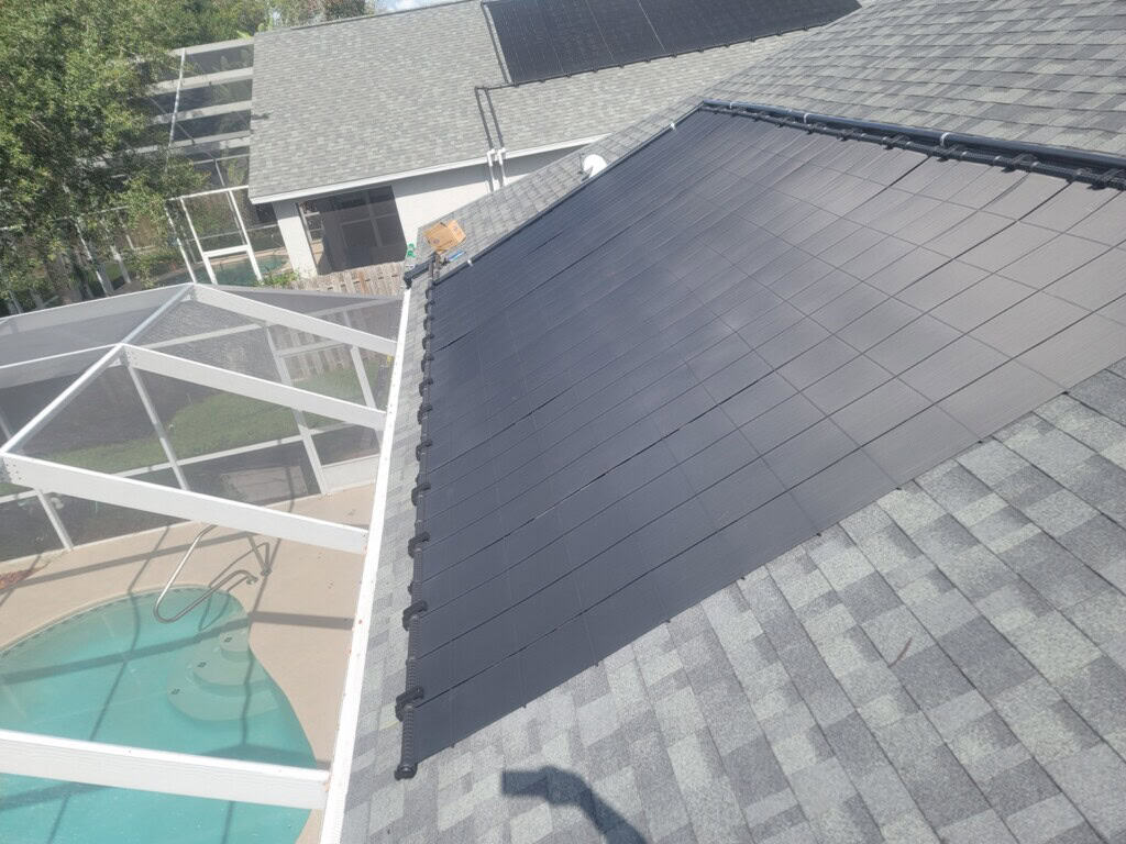 Rooftop solar pool heating collectors installed beside a screened swimming pool