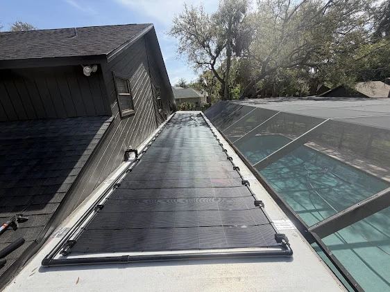 Sundial solar pool-heating collectors beside a screened pool in Ormond Beach