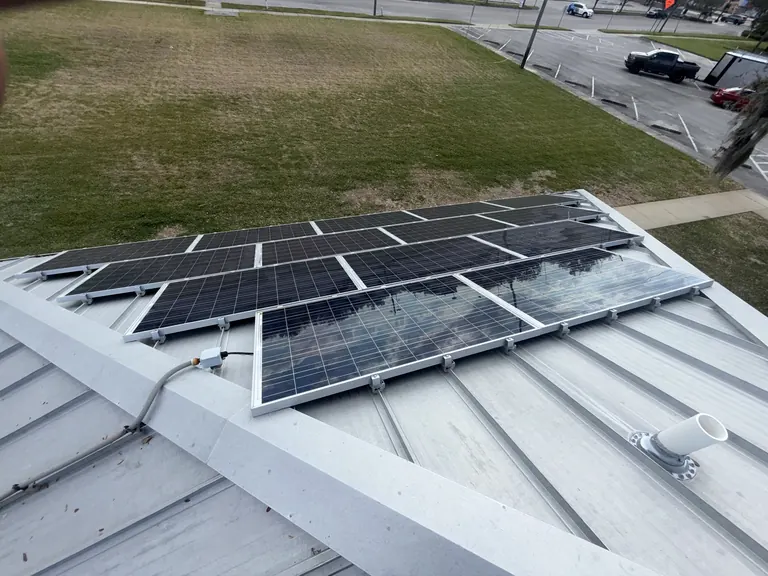 Original silver-framed solar panels on the Sanford facility metal roof.
